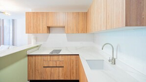 A modern kitchen with wooden cabinets, a white countertop, and a stainless steel faucet. - Amazing Loft in Casco Viejo (Panama City)