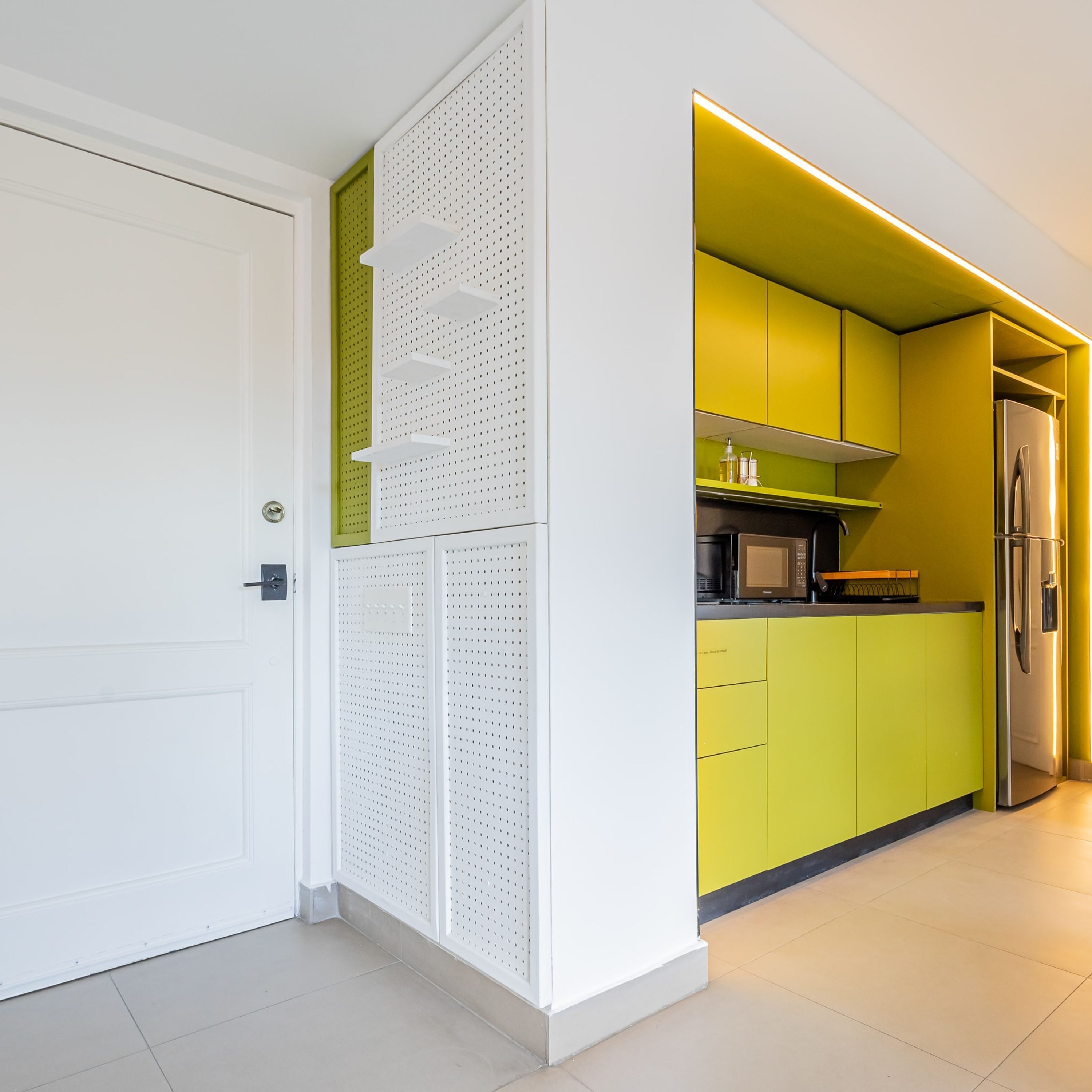 A modern kitchen with yellow cabinets, a stainless steel refrigerator, and a microwave.
