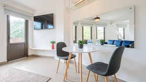 Un comedor moderno con una mesa redonda, dos sillas, un televisor de pantalla plana y un espejo grande que refleja la habitación.