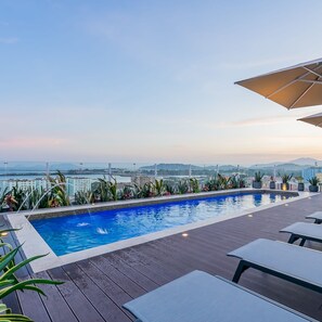 Une piscine sur le toit offrant une vue sur le paysage urbain et les montagnes au loin.