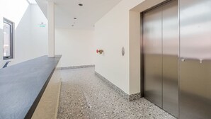A hallway with a reception desk, a fire alarm, and an elevator. - w Homey 1BR in Casco Antiguo (Panama City)