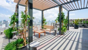 A rooftop garden with wooden pergola, seating, and potted plants. - Cozy 1BR With Balcony in Santa Ana (Panama City)