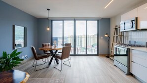 A modern kitchen with a large window, a dining area with a wooden table and chairs, and a view of the cityscape. - Cozy 1BR With Balcony in Santa Ana (Panama City)