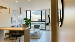 A modern living room with a dining area, large windows, and a view of the city. - w Amazing 1BR With Balcony in Chico (Bogotá)