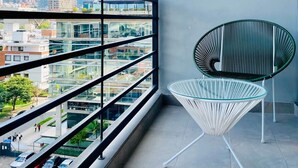 A balcony with a view of a cityscape, a white woven chair, and a green chair. - w Amazing 1BR With Balcony in Chico (Bogotá)