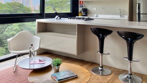 A modern kitchen with a large window, a built-in stove, and two bar stools. - w Captivating 1BR in El Poblado (Medellín)