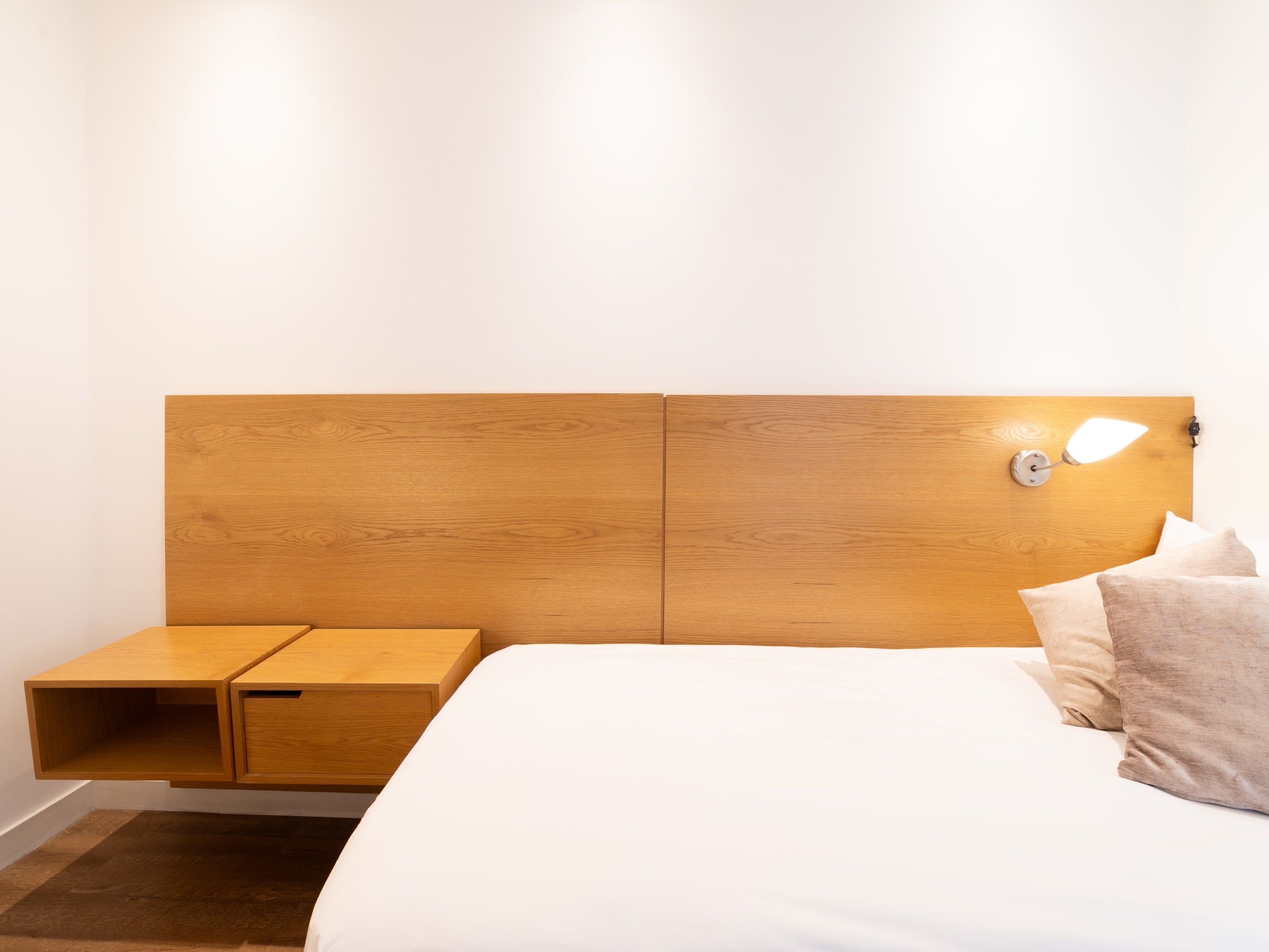 A modern bedroom with a wooden headboard, a bedside table, and a nightstand.