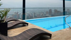 A rooftop pool with a city view, lounge chairs, and a concrete structure. - w Captivating 1BR in El Poblado (Medellín)