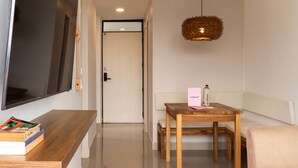 A modern living room with a flat-screen TV, a wooden coffee table, a dining table, and a hanging light fixture. - w Spectacular 1BR With Terrace at Poblado (Medellín)
