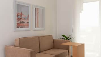 Uma sala de estar moderna com um sofá bege, uma pequena mesa de centro de madeira e duas obras de arte emolduradas na parede.