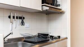 A modern kitchen with a stainless steel sink, a dish rack, and a microwave on a shelf. - w Spectacular 1BR With Terrace at Poblado (Medellín)
