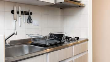Uma cozinha moderna com uma pia de aço inoxidável, um escorredor de louça e um micro-ondas em uma prateleira.