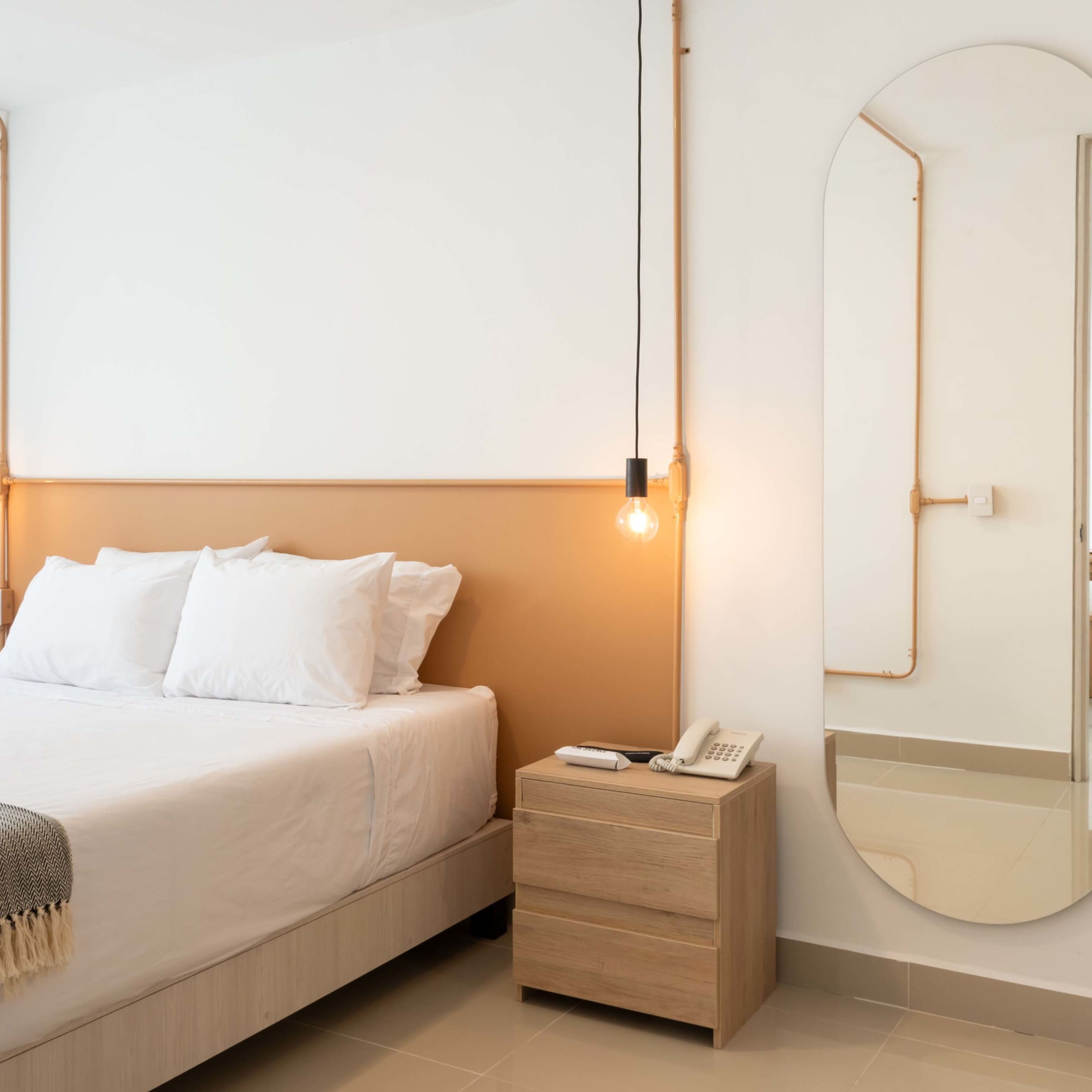 Quarto bem arrumado com cama, mesa de cabeceira e espelho.