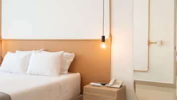 Quarto bem arrumado com cama, mesa de cabeceira e espelho.