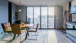 En moderne stue med spiseplads, store vinduer og udsigt over byen.