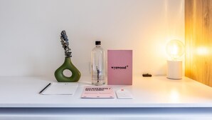A white desk with a pen, a welcome card, a bottle, a pink box, and a light bulb. - w Phenomenal Loft in Chapinero (Bogotá)