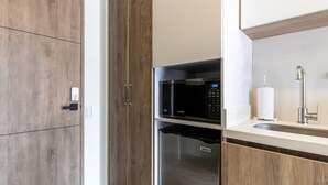 A modern kitchen with wooden cabinetry, a stainless steel refrigerator, a microwave, and a sink with a faucet. - w Phenomenal Loft in Chapinero (Bogotá)