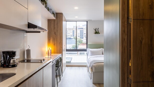 A modern kitchen with a coffee maker, a sink, and a window overlooking a cityscape. - w Phenomenal Loft in Chapinero (Bogotá)