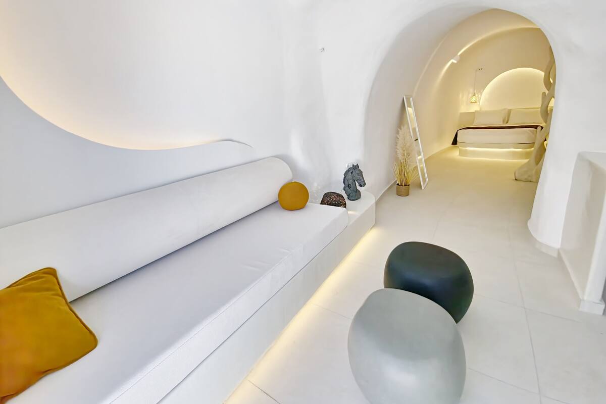 A modern, minimalist interior with a white color scheme, featuring a sofa, a small table, and a decorative horse statue.