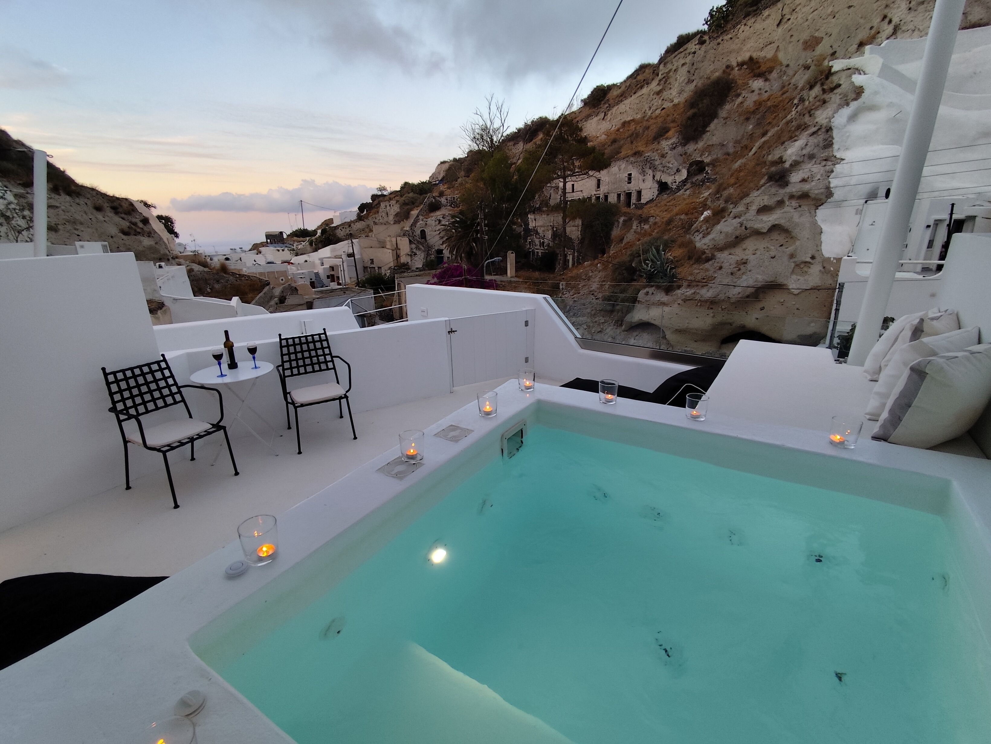 Un área de piscina en la azotea con vista a edificios blancos y colinas rocosas.