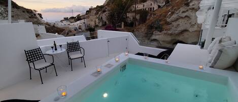 Un área de piscina en la azotea con vista a edificios blancos y colinas rocosas.