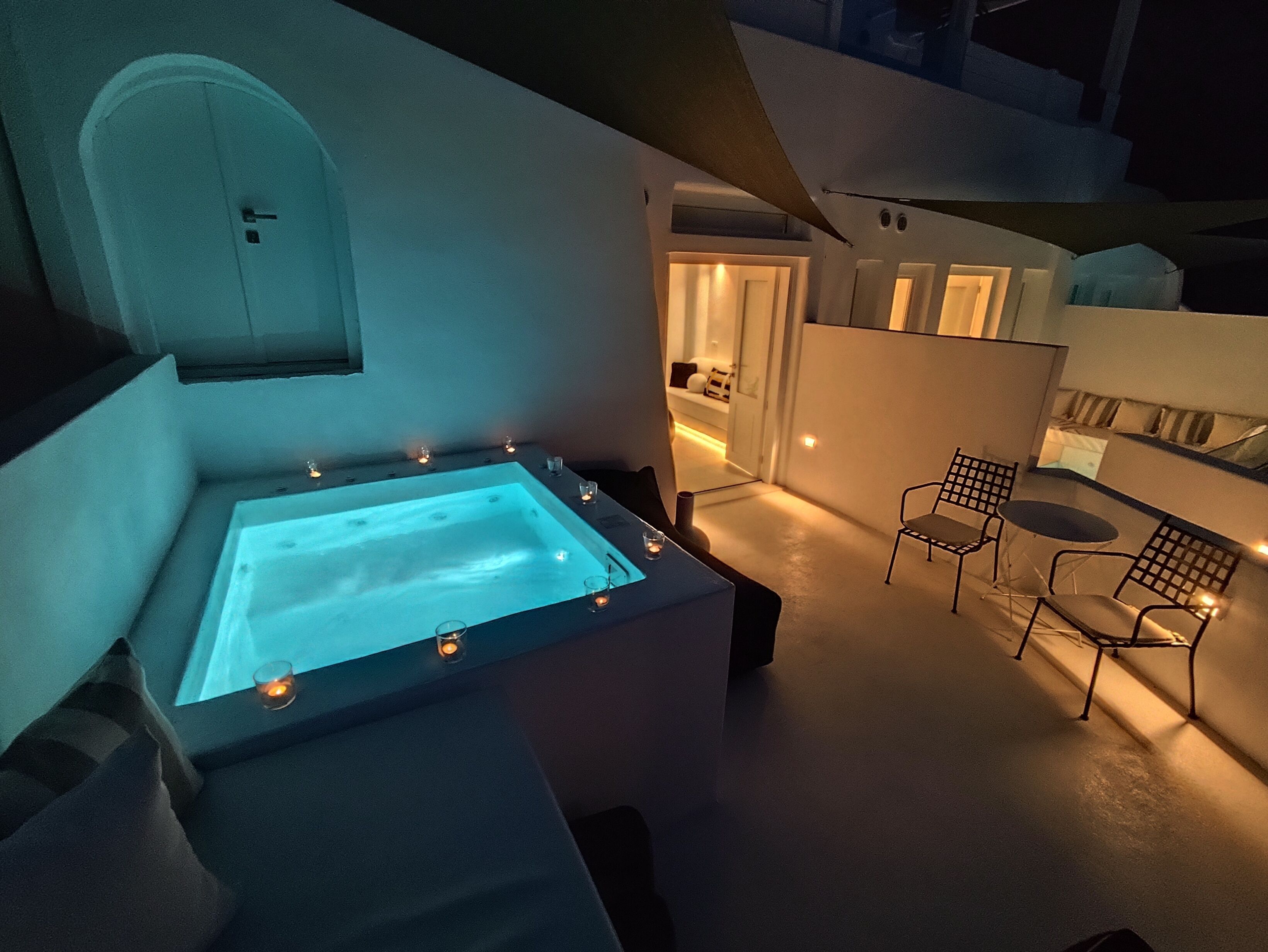 A modern outdoor jacuzzi area with a heated pool, seating, and ambient lighting.