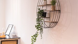 A wall-mounted metal shelf with three tiers, each holding a potted plant.