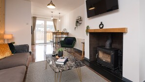 A modern living room with a sofa, coffee table, fireplace, and a TV mounted on the wall.