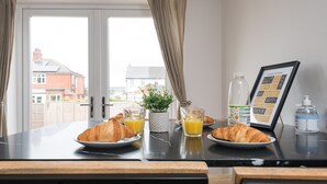 A breakfast table with croissants, orange juice, and a menu.