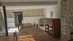 A spacious dining area with a large wooden table and chairs, a stone accent wall, and a kitchen area with a stone wall and wooden cabinets.