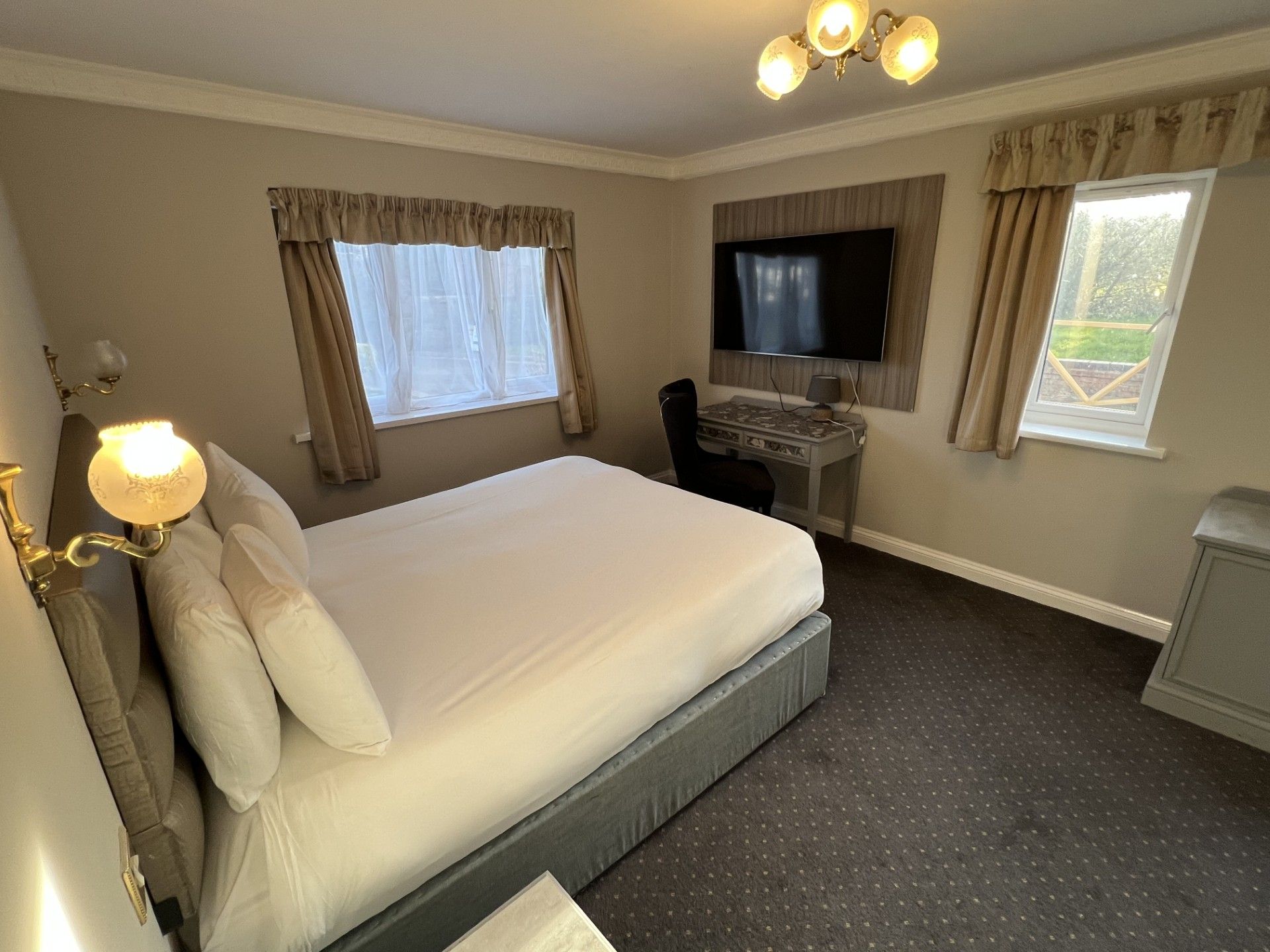 A hotel room with a bed, a desk, a television, and a window.