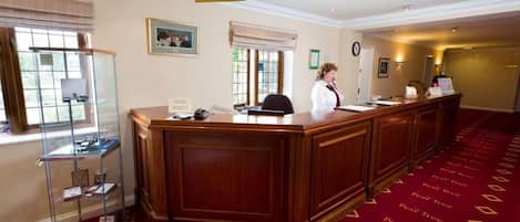 A reception area with a wooden reception desk, a glass display case, and a red carpet with 'Pearl Tree' branding.
