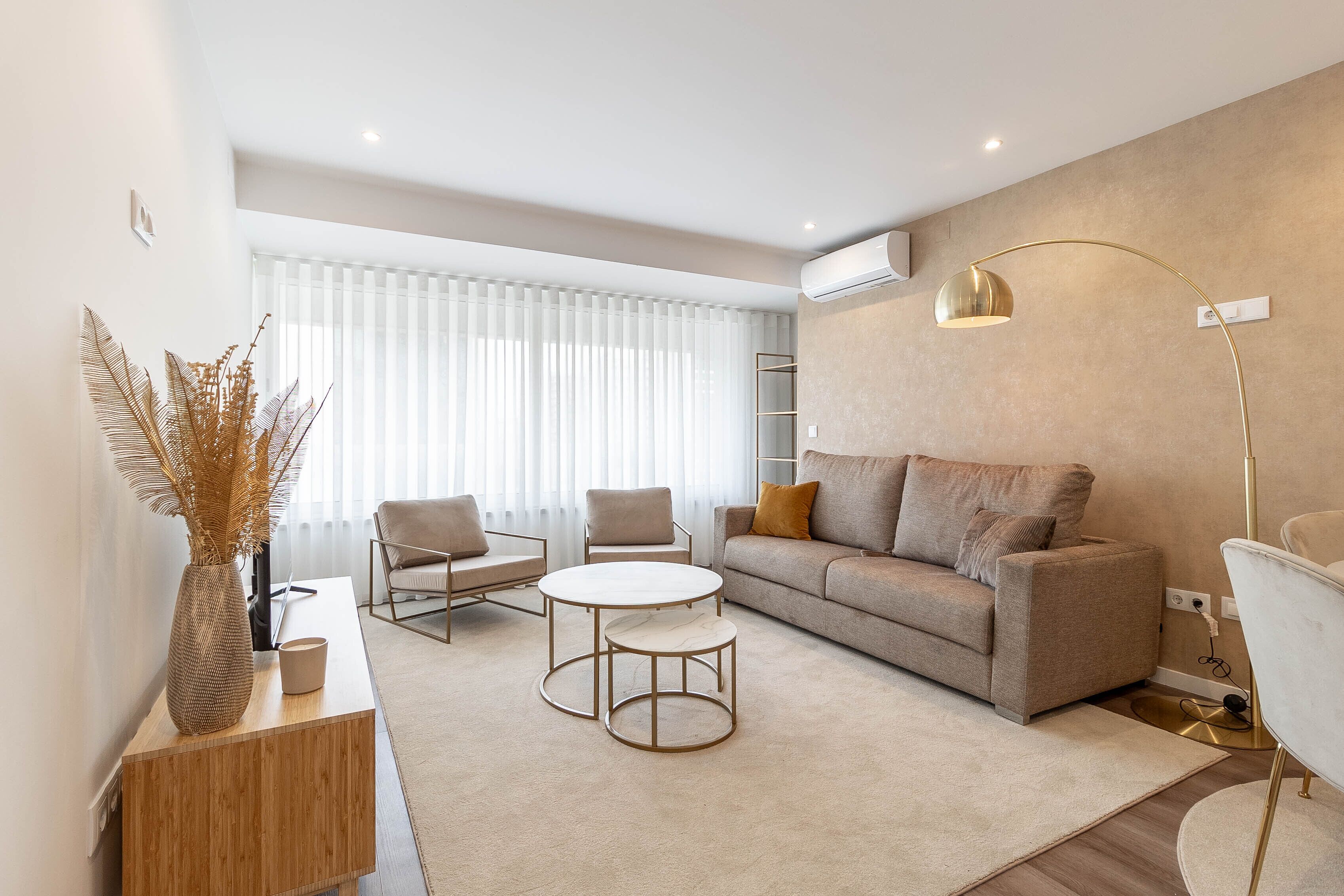 Uma sala de estar moderna com um sofá, duas poltronas, uma mesa de centro e um abajur.