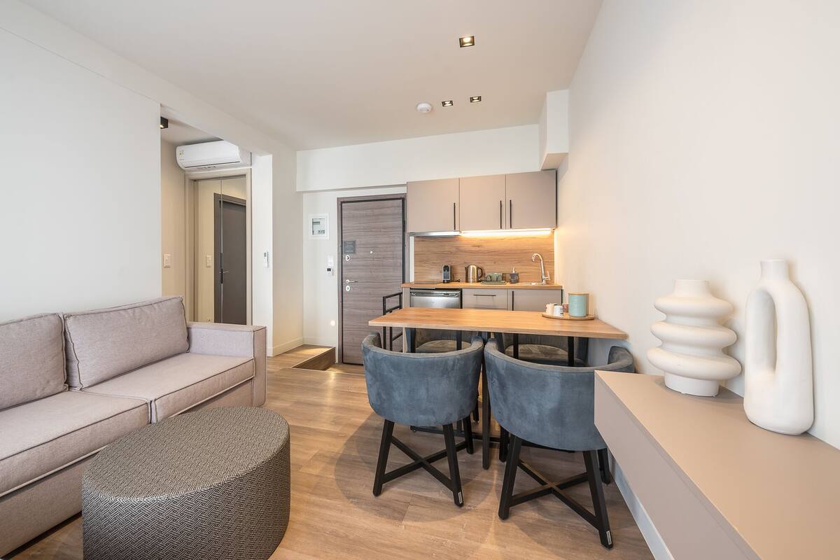 A modern kitchen with a wooden table and chairs, a built-in oven, and a coffee machine.