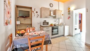 Cozinha moderna com mesa de jantar posta para dois, micro-ondas, forno e frigorífico.