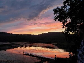 Un coucher de soleil sur un lac, avec une jetée qui s’avance dans l’eau.