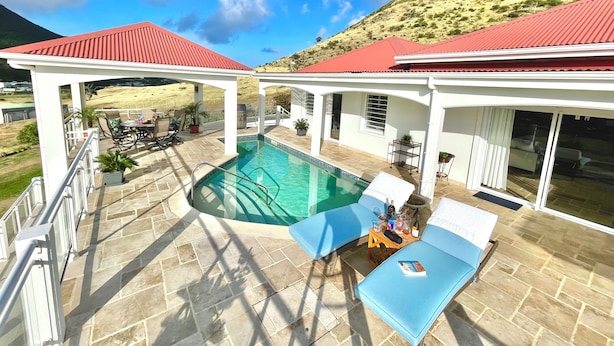 Un espace aménagé au bord de la piscine, comprenant une piscine, des chaises longues et un patio couvert.