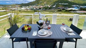 Une table à manger installée à l’extérieur, offrant une vue sur une montagne et une ville en arrière-plan.