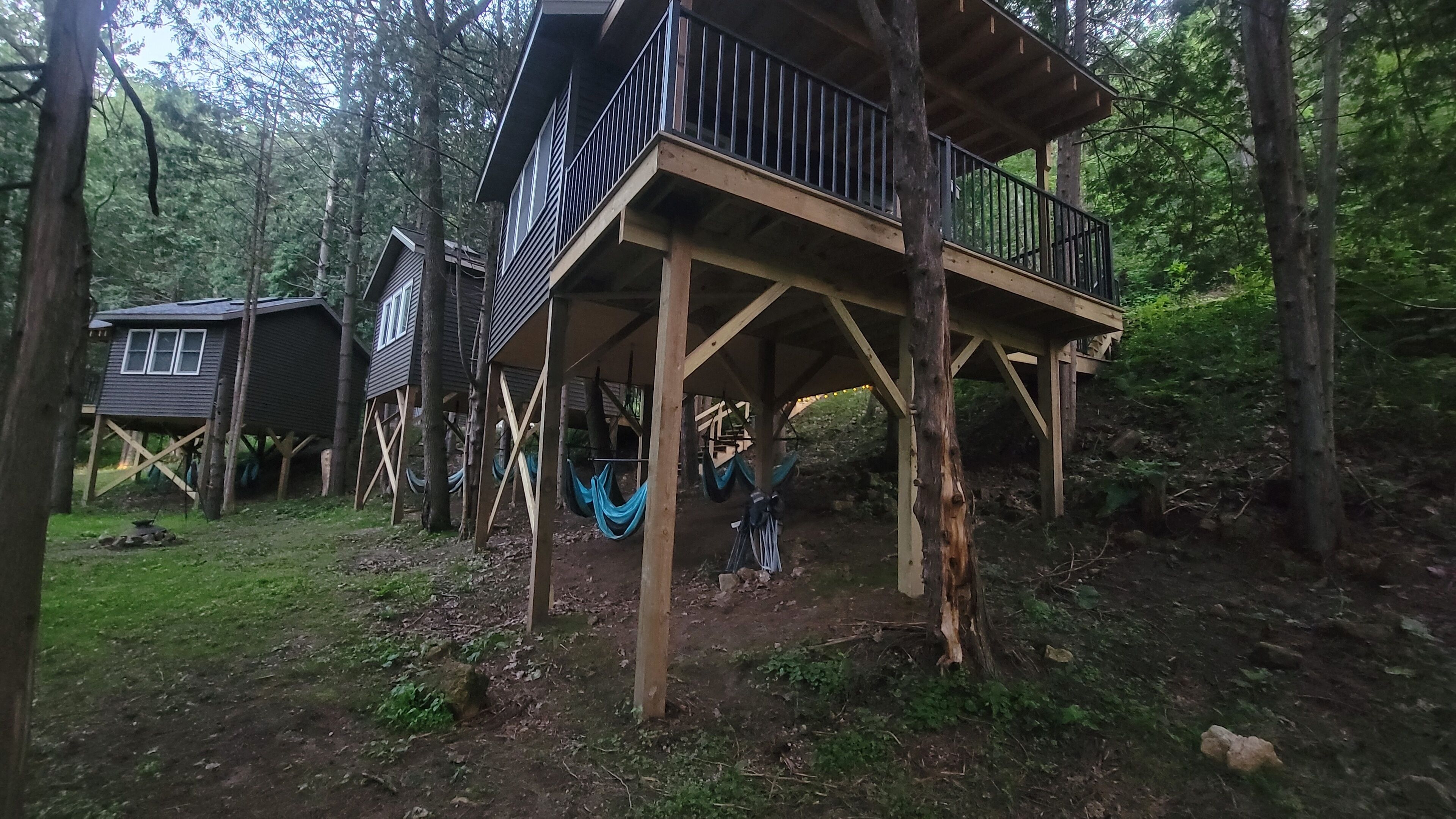 Una cabaña en el bosque con terraza de madera y varios niveles.