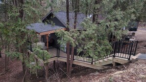 A wooden cabin with a deck, surrounded by trees. - Tiny Treehouse Cabin | Bluff Woodlands #1 (Elba)