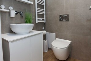 Een moderne badkamer met een wit wastafel, toilet en handdoekrek.