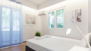 A modern bedroom with a bed, a bedside lamp, a potted plant, and artwork on the wall. - Kipseli New Modern Cosy Apartments No 1 (Athens)