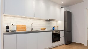 A modern kitchen with white cabinets, a wooden countertop, a built-in oven, and a stainless steel refrigerator. - Kipseli New Modern Cosy Apartments No 1 (Athens)