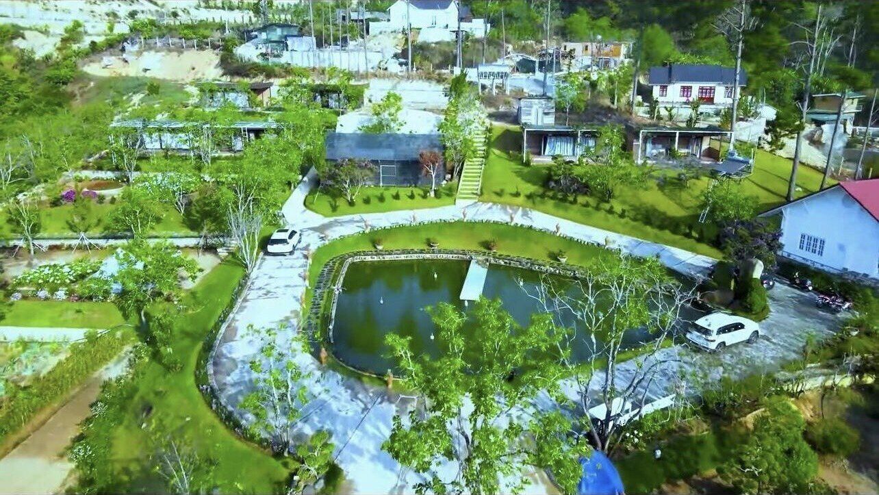 A residential area with a central pond, surrounded by greenery and houses.