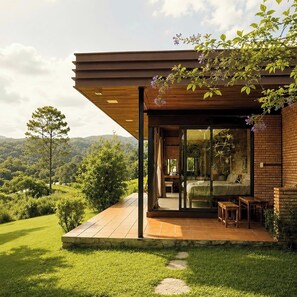 A modern house with a wooden deck, a glass door leading to a bedroom, and a view of the surrounding landscape. - Scent Bungalow (Xuan Huong - Da Lat)