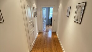 A hallway with wooden flooring, white walls, and framed pictures. - Haus in Köln Thielenbruch (Köln)