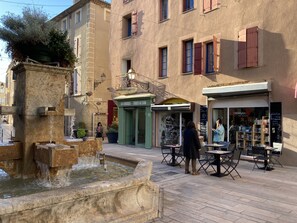 A public square with a fountain, outdoor seating, and storefronts including a bakery and a bookstore. - Aux 4 Fontaines - Dreizimmerwohnung Mitten im Historischen Zentrum von Narbonne (Narbonne)