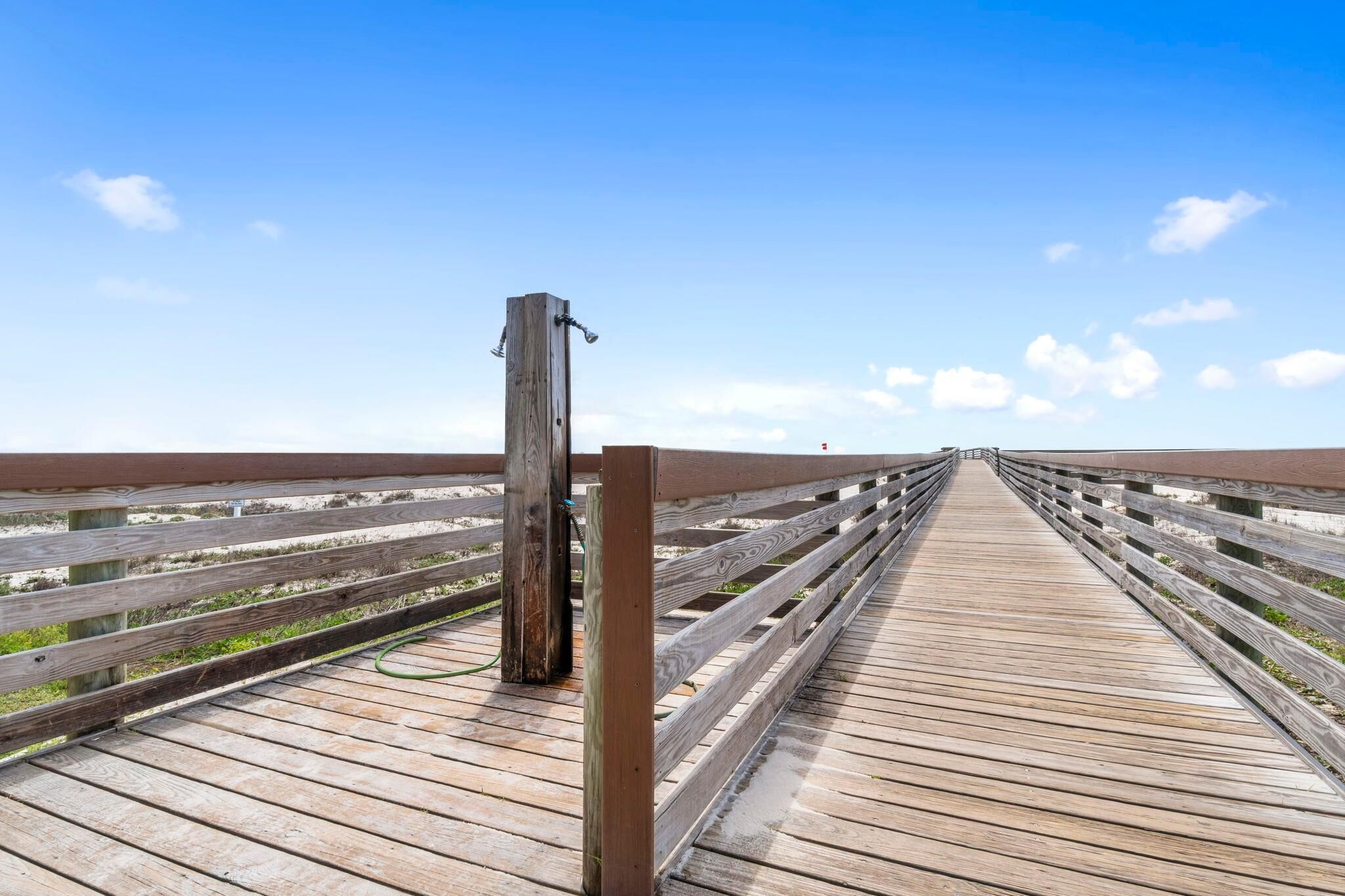 Una pasarela de madera que se extiende hasta el horizonte bajo un cielo despejado.
