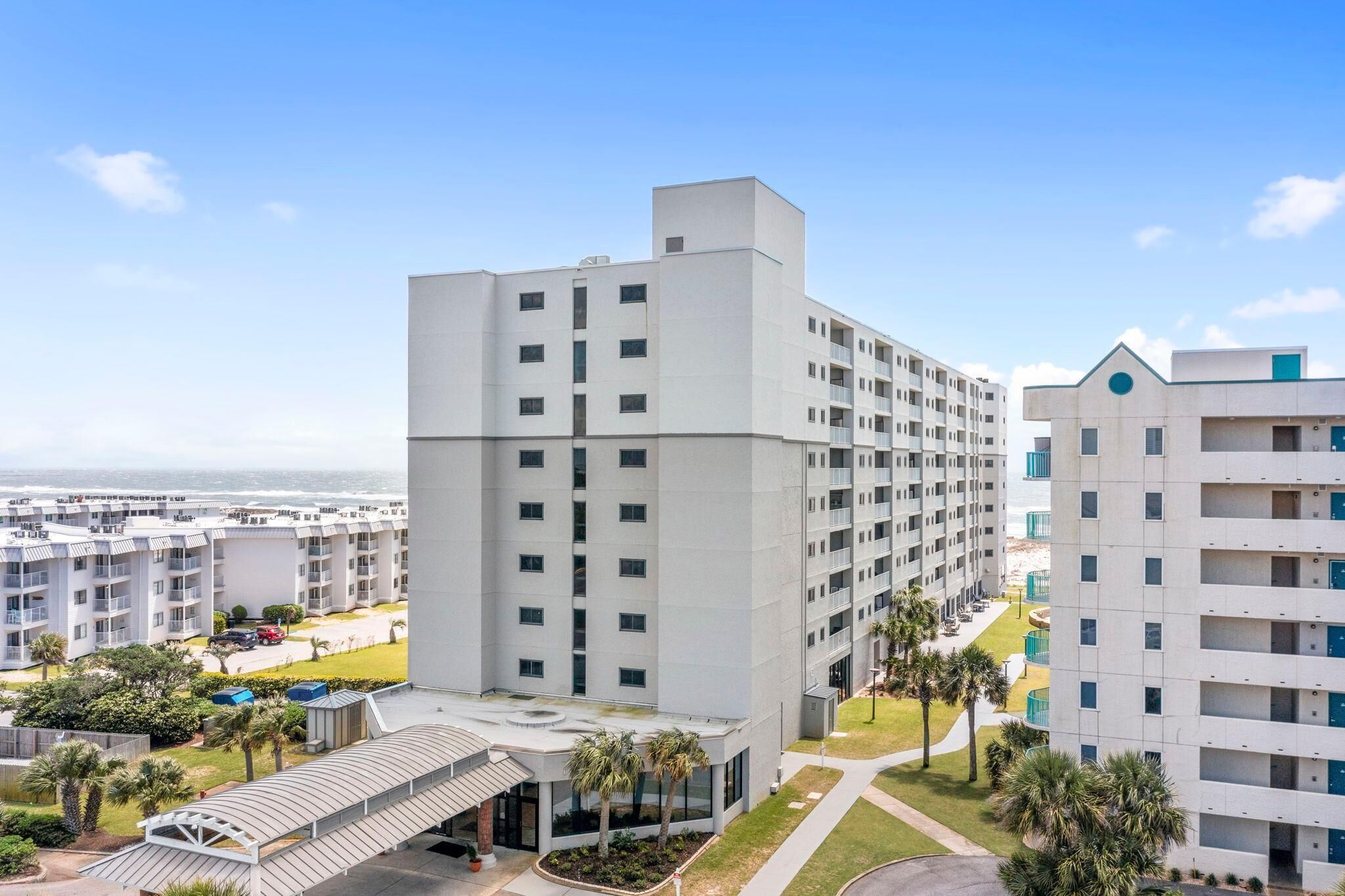 A modern hotel with multiple floors, a covered entrance, and a view of the beach.