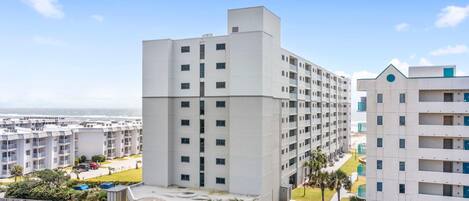 A modern hotel with multiple floors, a covered entrance, and a view of the beach.